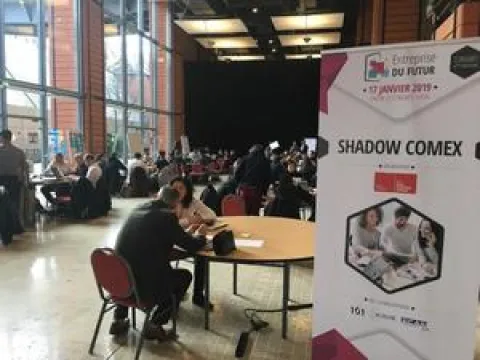IA, transformation digitale, co-working - super héros de l’entreprise du futur Une grande salle avec des personnes assises à des tables, discutant et interagissant dans un environnement convivial.